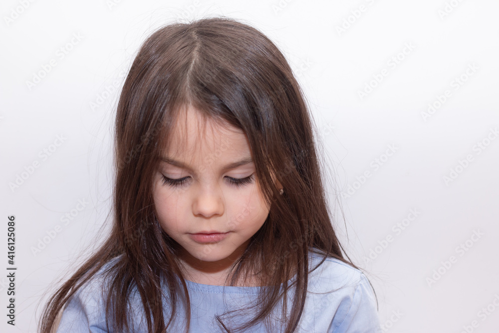Beautiful little cute girl with long smooth hair looks down with interest Beautiful little cute girl with long smooth hair looks down with interest