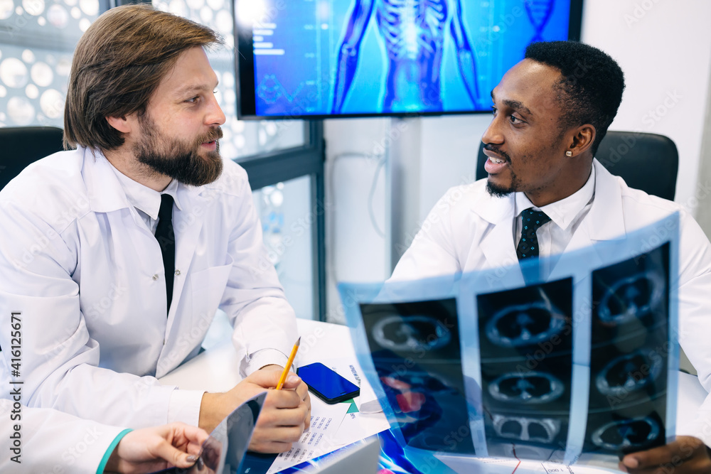 Fototapeta premium Two doctors look at x-rays and discuss the diagnosis. They sit a