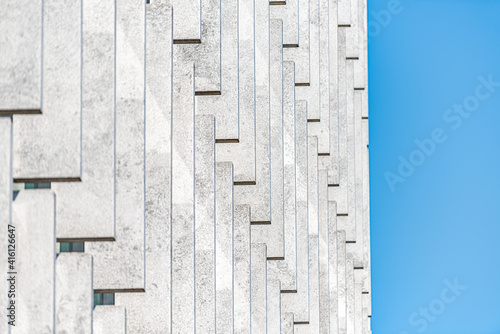 Abstract pattern closeup of contemporary modern architecture building with white vertical lines facade exterior design and blue sky