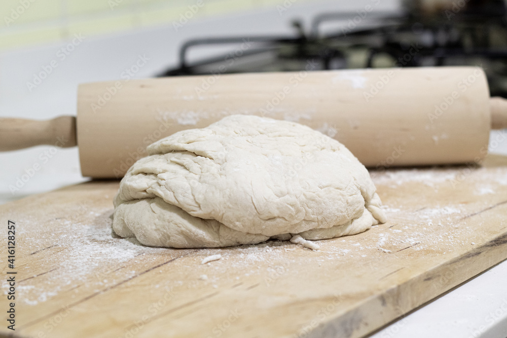 Dough in a wooden table with a rolling pin Dough in a wooden table with a rolling pin