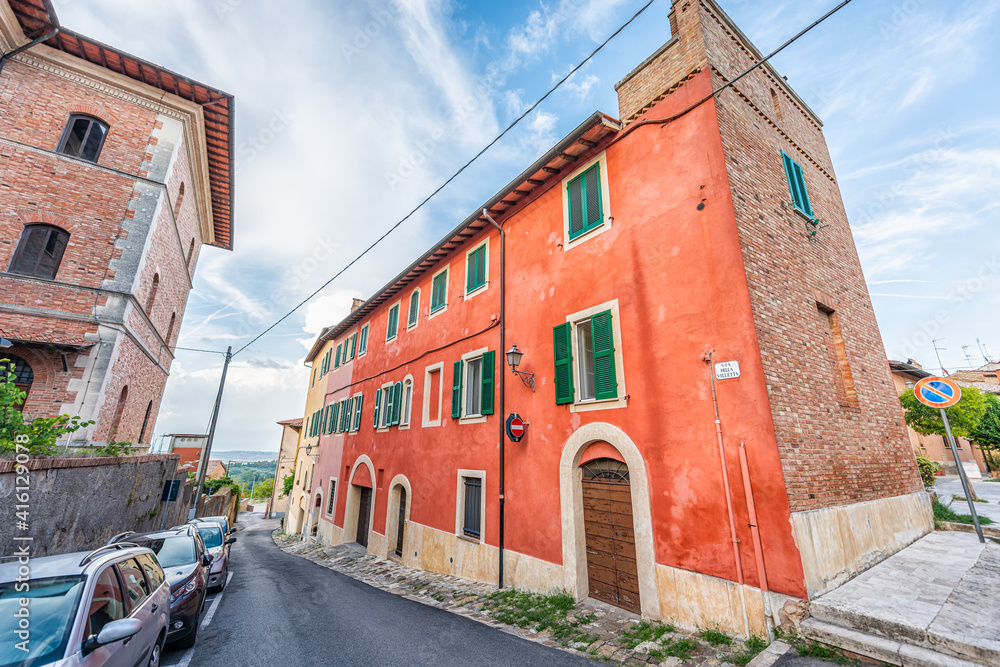 Chiusi, Italy small historic town village city in Tuscany with colorful red house building during summer and sign for via della villetta and nobody