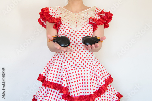 Detalle de una mujer española vestida con un vestido de lunares rojos de flamenca tocando las castañuelas. Concepto de bailarina de sevillanas. Flamenco. photo