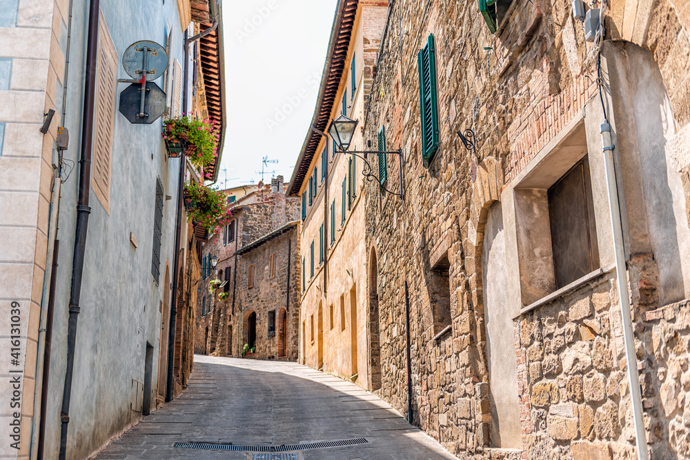 Montalcino, Italy town village in Tuscany during summer day with narrow alley and stone walls hanging flowers potted plants and nobody