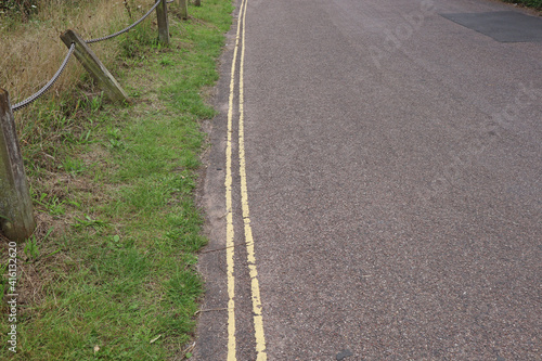 Double yellow lines on a narrow country lane, meaning no parking is allowed