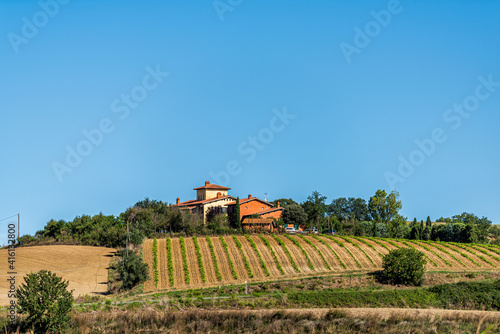 Fotografie Tuscany, Italy landscape with trees and hilltop house villa with green farm row