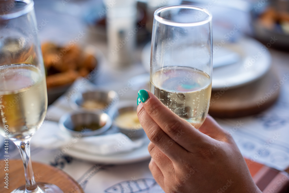 Woman with manicured nails holding glass of champagne