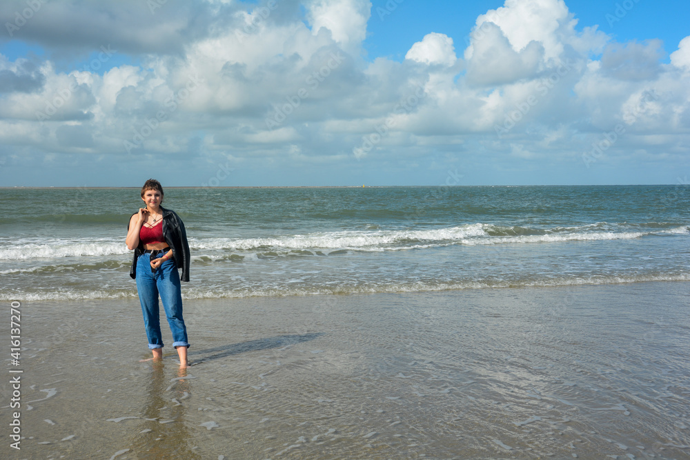 A young woman stands in the waves on the beach