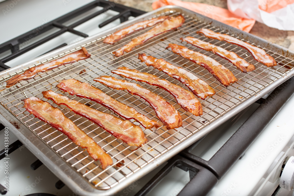 A closeup view of a tray of baked bacon strips.