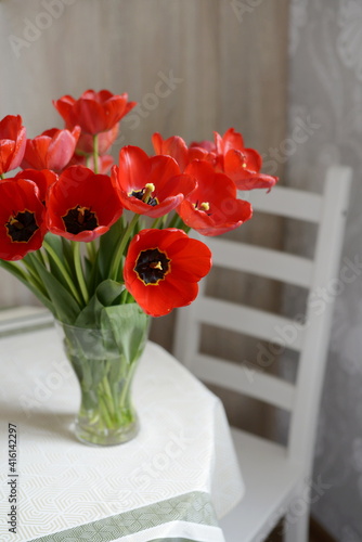 blooming red tulips in the vase on the table