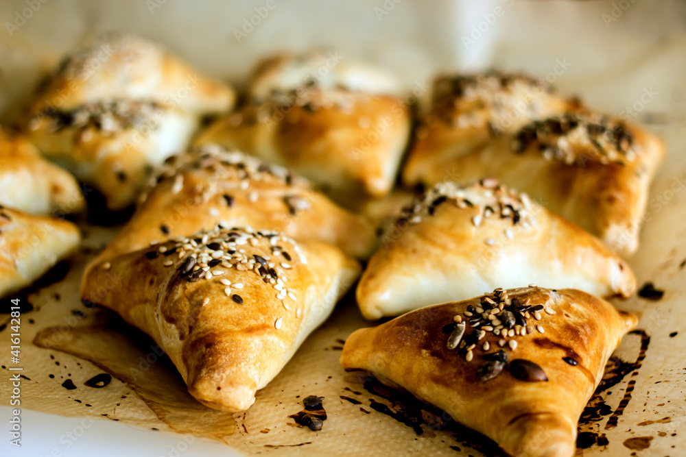 Samsa oriental Uzbek puff pastry pies with meat and pumpkin on a plate on the table, close-up. Triangular pies with sesame seeds, national authentic pastries