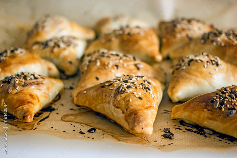 Samsa oriental Uzbek puff pastry pies with meat and pumpkin on a plate on the table, close-up. Triangular pies with sesame seeds, national authentic pastries
