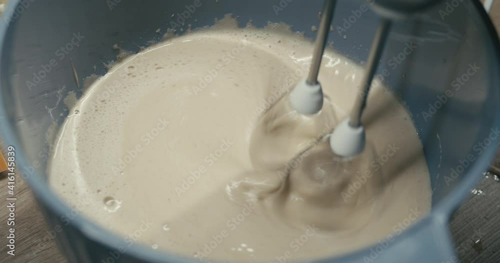 Baker using electric mixer in a bowl for mixing ingredients of a sweet cake dessert in a home kitchen Baker using electric mixer in a bowl for mixing ingredients of a sweet cake dessert in a home kitchen
