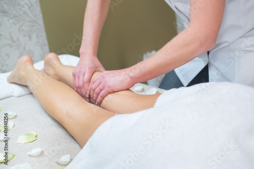 professional beautician massaging legs of female customer