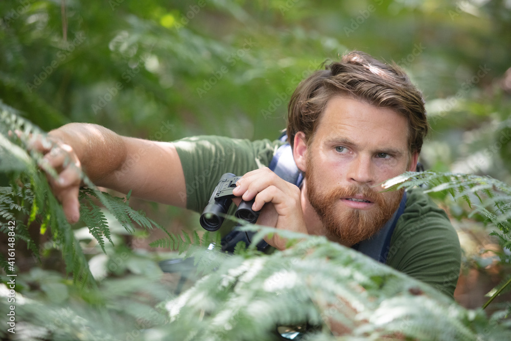 tourist looking through binoculars hiding in trees tourist looking through binoculars hiding in trees