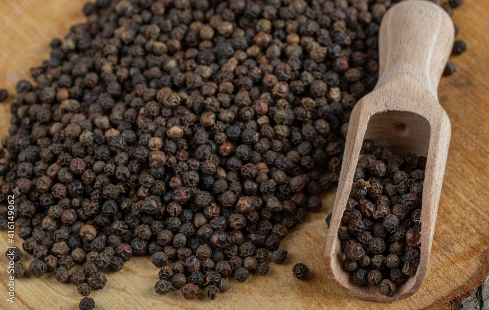 A wooden board with dried peppercorn on a gray background A wooden board with dried peppercorn on a gray background