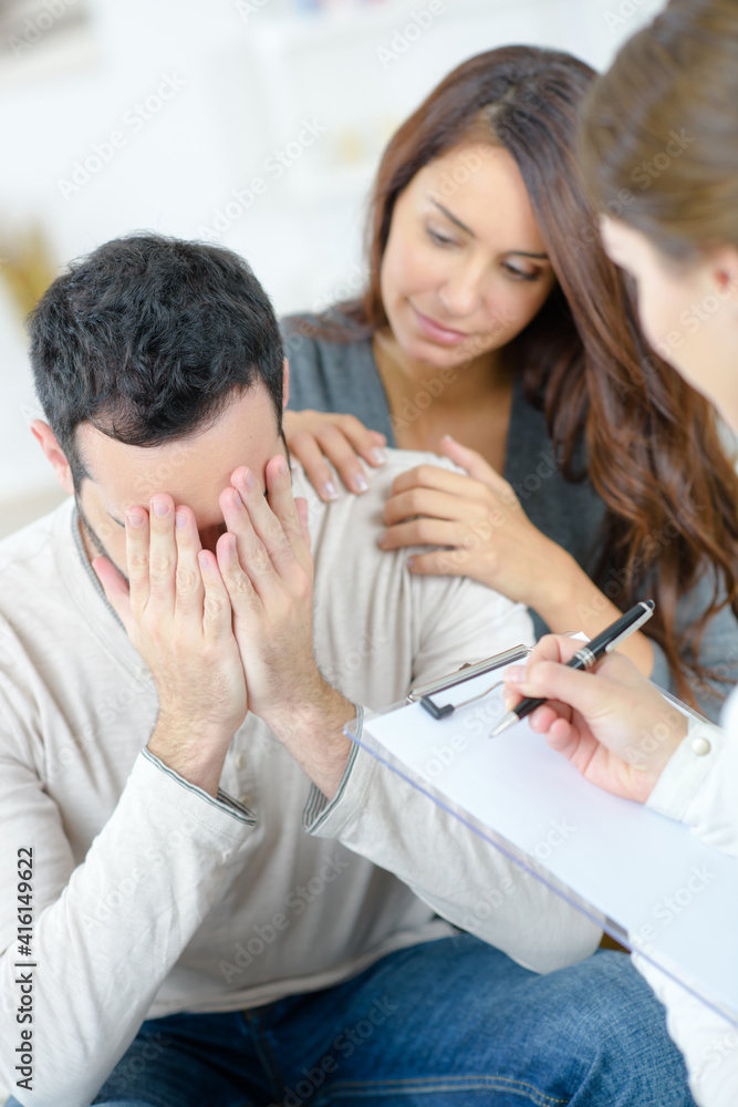 Woman comforting tearful man in therapy Woman comforting tearful man in therapy