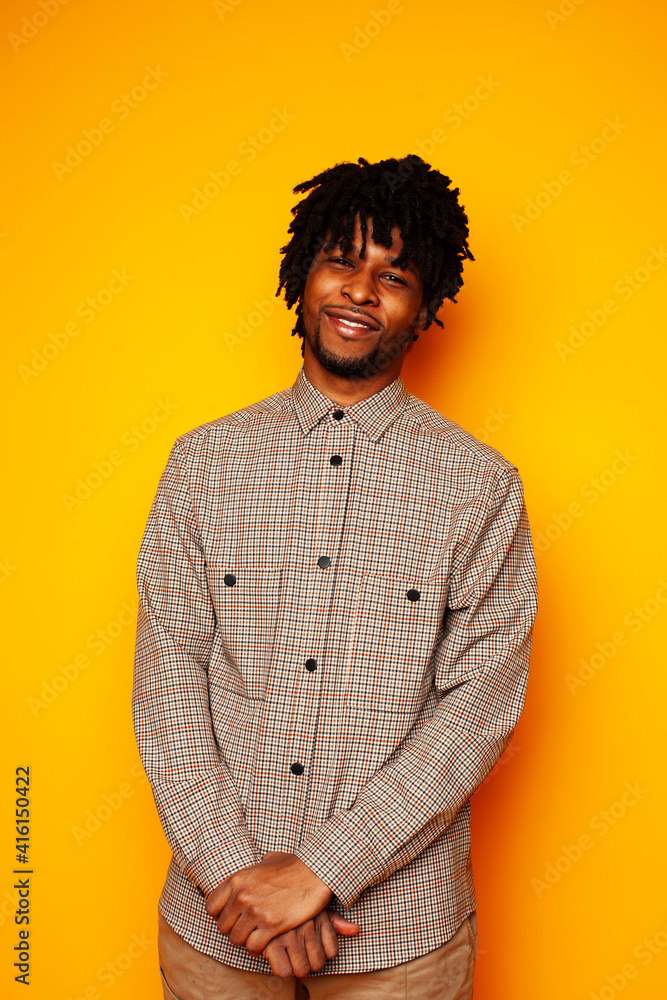 Fototapeta premium young handsome african american guy student posing cheerful and gesturing on yellow background, lifestyle people concept