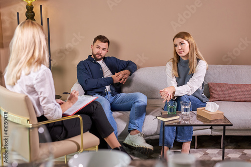 Disappointed couple at reception with family therapist, explaining problem,caucasian female doctor listening man and woman in bad mood. Family relationship disorder concept