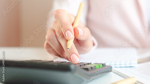 close up of woman hand with calculator counting and taking notes to notebook