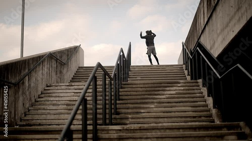 Young male athlete in sportswear being happy after finishing his workout exercise outside in urban environment in the morning. Sports and urban concept.