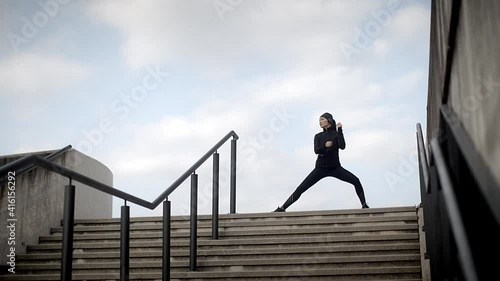 Young, attractive asian woman in sportswear doing stretching exercise outside in the morning before a workout. Sports and urban concept.