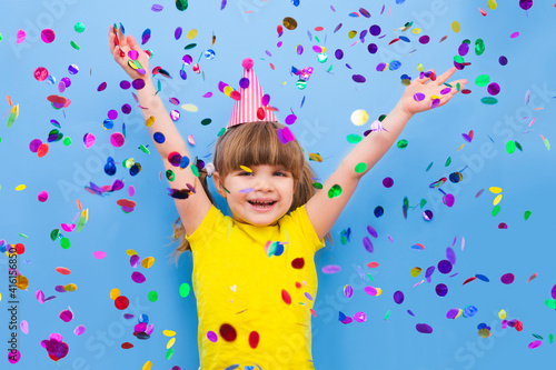 happy child girl with confetti on blue background 
