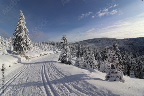 A beautiful snowy path in mountains with blue sky above in Jeseniky, Czech republic