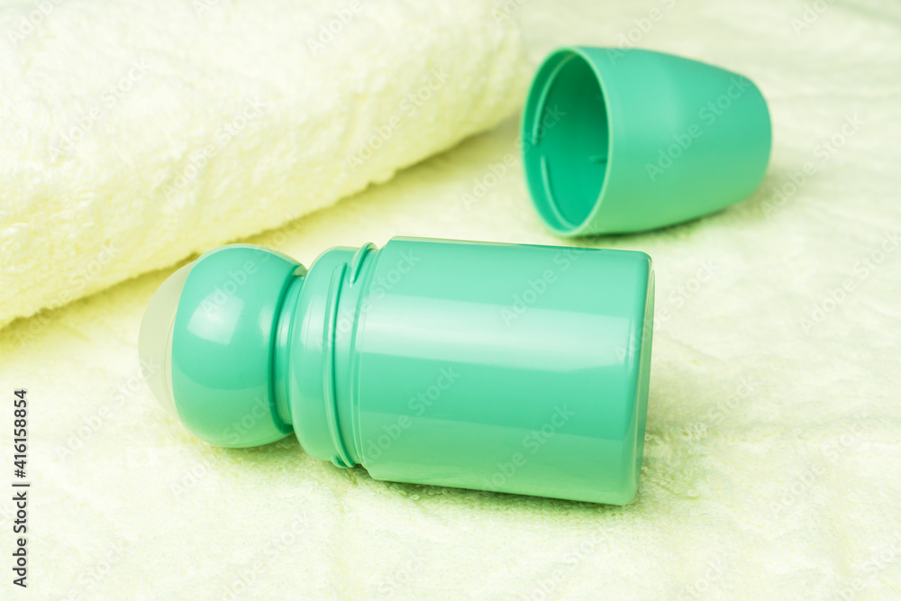 Bottle of roll on antiperspirant deodorant lying on the background of bath towels. Personal hygiene and body care concept. Bottle of roll on antiperspirant deodorant lying on the background of bath towels. Personal hygiene and body care concept.