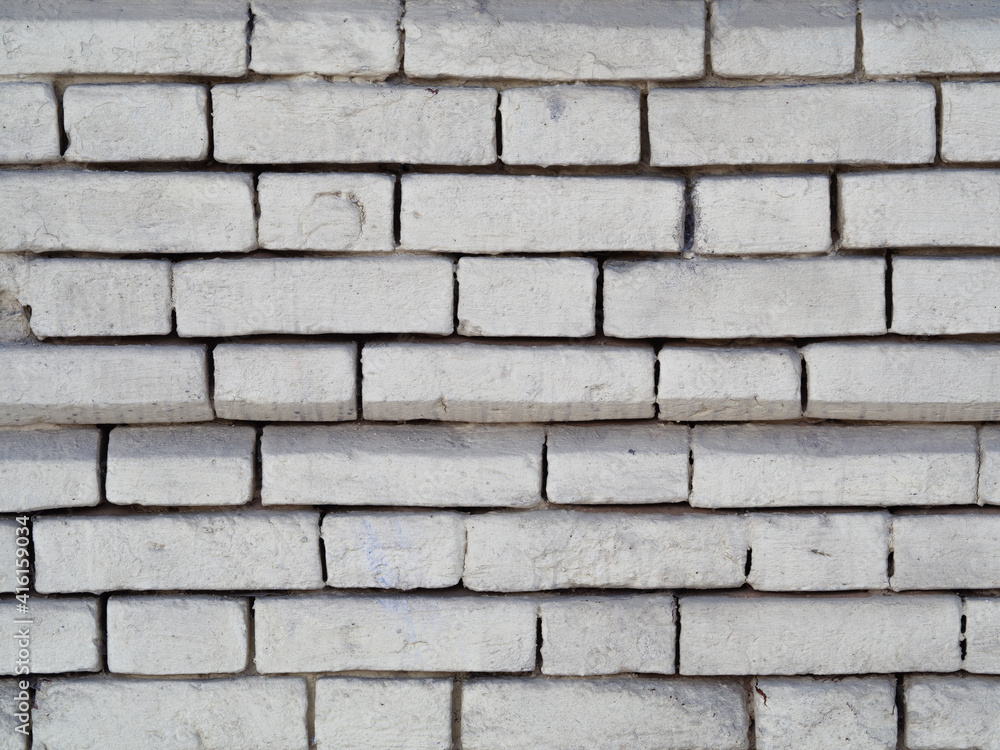 White brick background (pattern) of rough, uneven, carelessly painted over with paint or plaster. The textured surface of the old exterior walls of an industrial building. Chips, cracks and protrusion White brick background (pattern) of rough, uneven, carelessly painted over with paint or plaster. The textured surface of the old exterior walls of an industrial building. Chips, cracks and protrusion