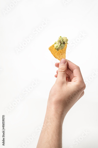 hand holding a tortilla chip with guacamole 