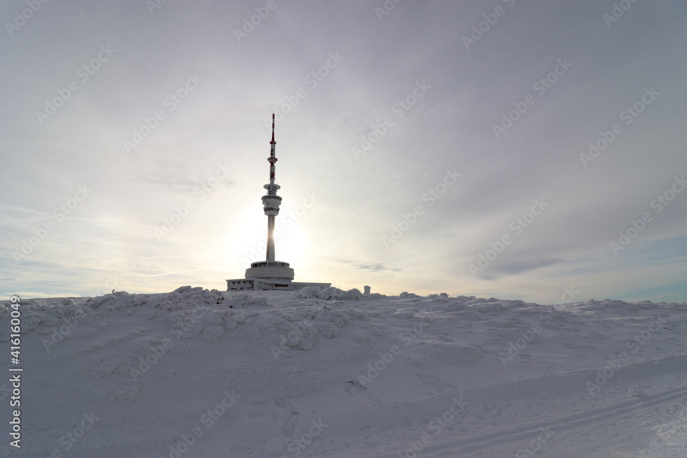 A winter view to the lookout tower with sun in background at Praded, Czech republic
