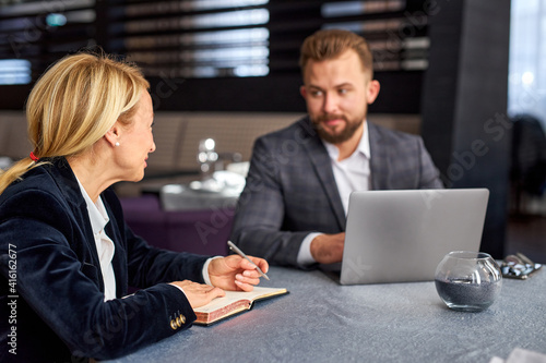 business partners have conversation and talking at meeting in restaurant, they sit with laptop at table, co-working, wearing formal clothes. focus on woman talking