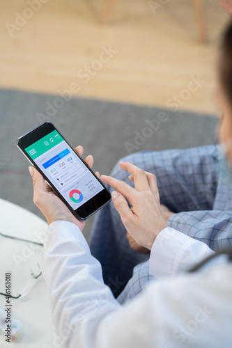 Doctor pointing at smartphone display with results of individual health program