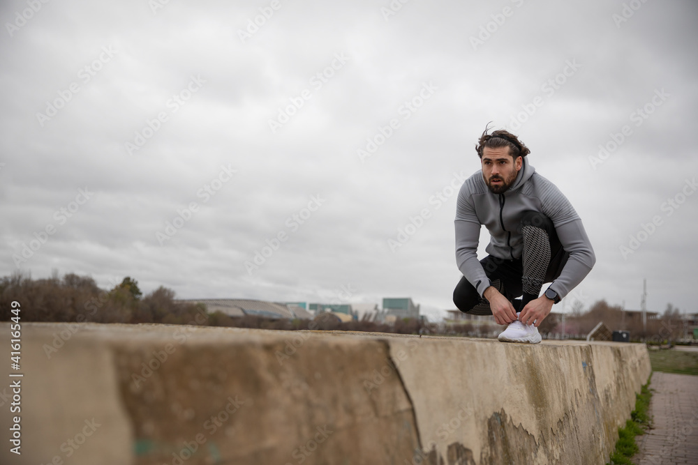 Fototapeta premium Ahtlete tying shoelaces and getting ready for running on a cold day