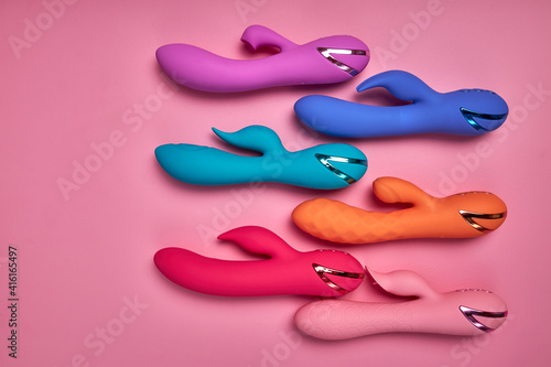 Bright Colorful G-spot Vibrators Arranged On Pink Paper Background, Big Variety Of Dildo Colours. Copy Space, Flat Lay
