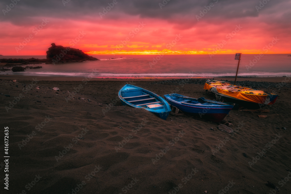 Fototapeta premium atardecer con barcas en la arena
