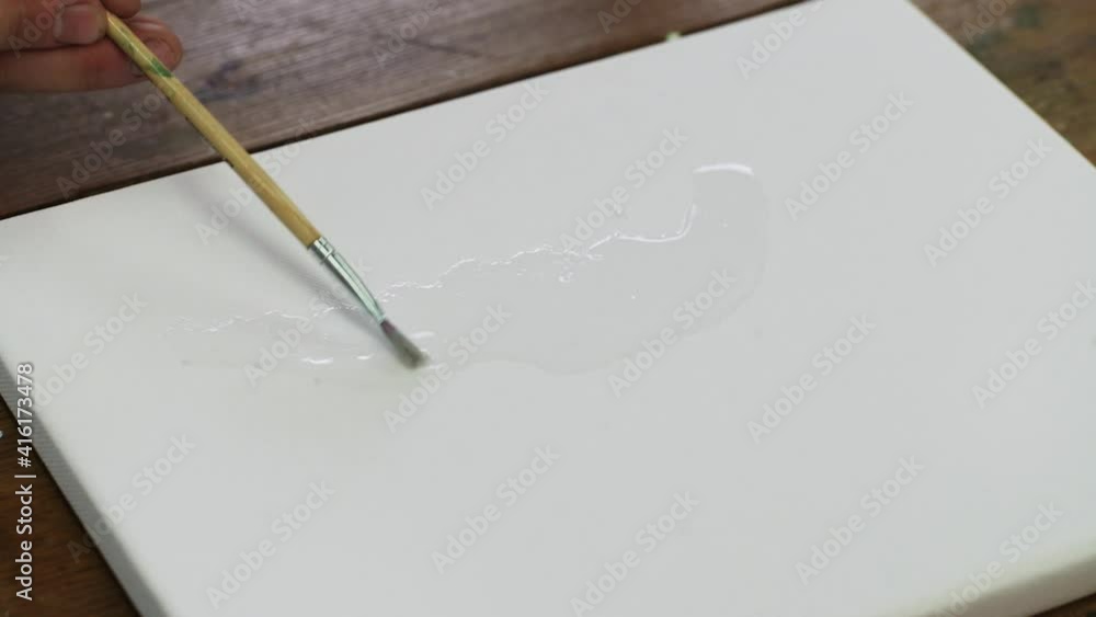 Close up of artist paints an abstract picture, she uses paintbrush to distribute water on canvas Close up of artist paints an abstract picture, she uses paintbrush to distribute water on canvas