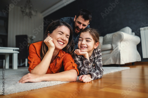 Happy family spending quality time together. They lying on the floor and laughing.