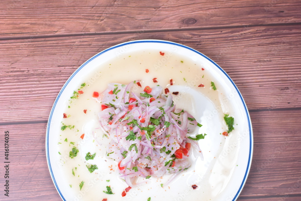 Traditional Peruvian ceviche with fish, onion, lemon, chili peppers, coriander, salt and pepper on wooden background Traditional Peruvian ceviche with fish, onion, lemon, chili peppers, coriander, salt and pepper on wooden background