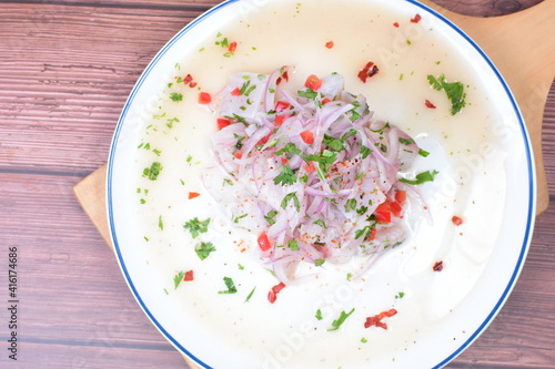 Traditional Peruvian ceviche with fish, onion, lemon, chili peppers, coriander, salt and pepper on wooden background