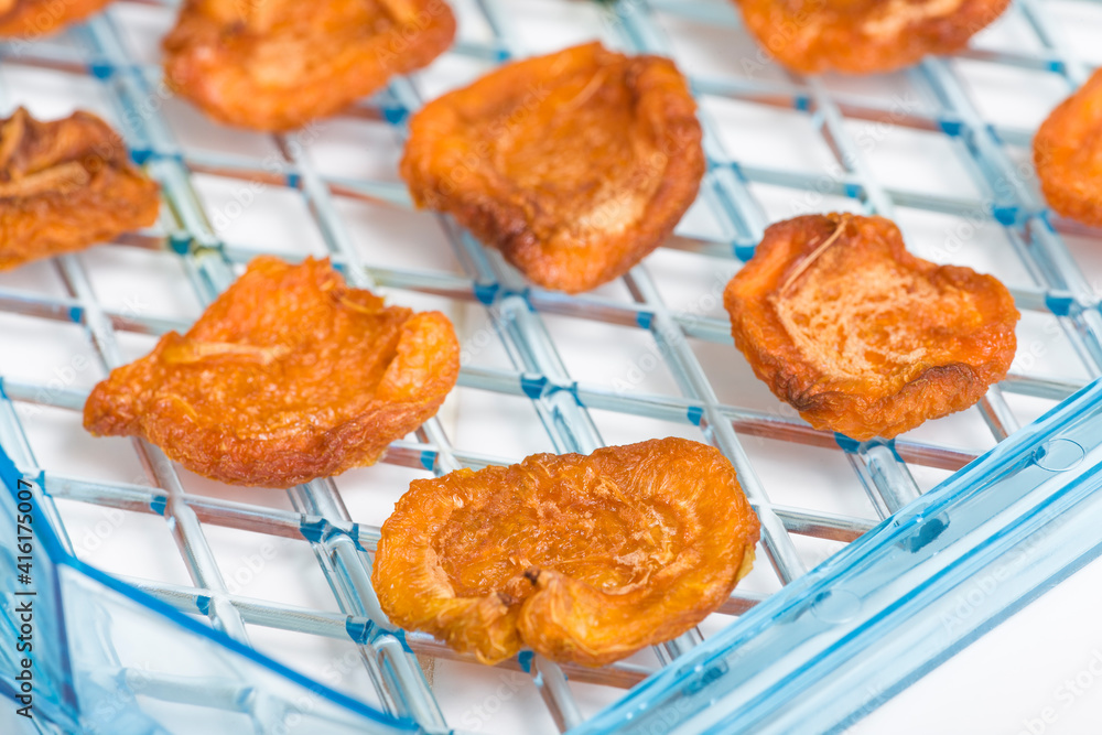 Dehydrator tray of homemade dried apricots, ready to be eaten. The holes in the tray allow the air to circulate freely and assure all fruit is dried evenly. Dehydrator tray of homemade dried apricots, ready to be eaten. The holes in the tray allow the air to circulate freely and assure all fruit is dried evenly.