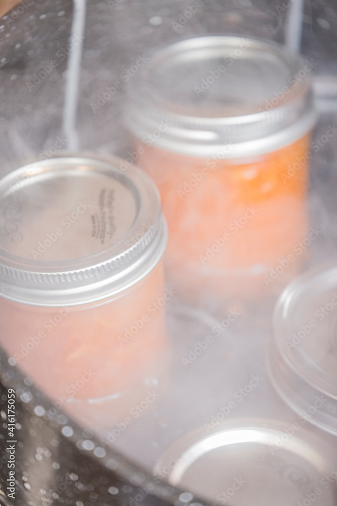 Jars of apricot jam resting on a canner rack in a boiling water canner. Canner racks simplify the canning process by helping you safely get a load of jars into and out of a pot of boiling water.