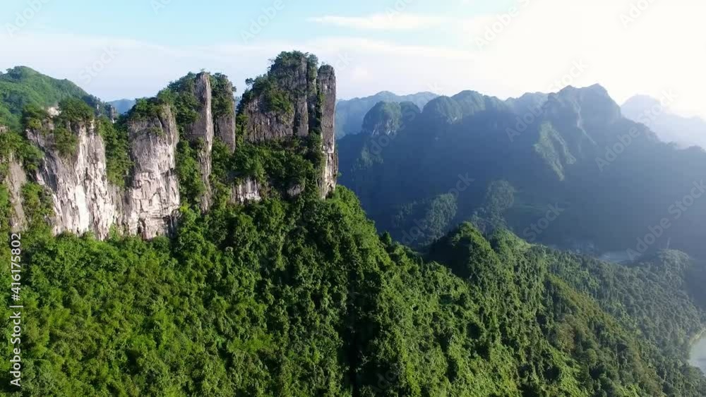 Drone view from a peculiar mountain peak to green mountains and a river flowing in the valley Drone view from a peculiar mountain peak to green mountains and a river flowing in the valley