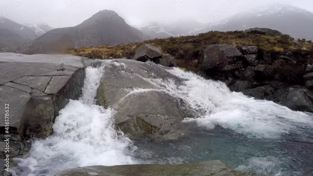Moody and cold waterfall with foggy mountains in the background. The video was taken on a misty day on the Isle of Skye, the mystical island of Scotland. Moody and cold waterfall with foggy mountains in the background. The video was taken on a misty day on the Isle of Skye, the mystical island of Scotland.