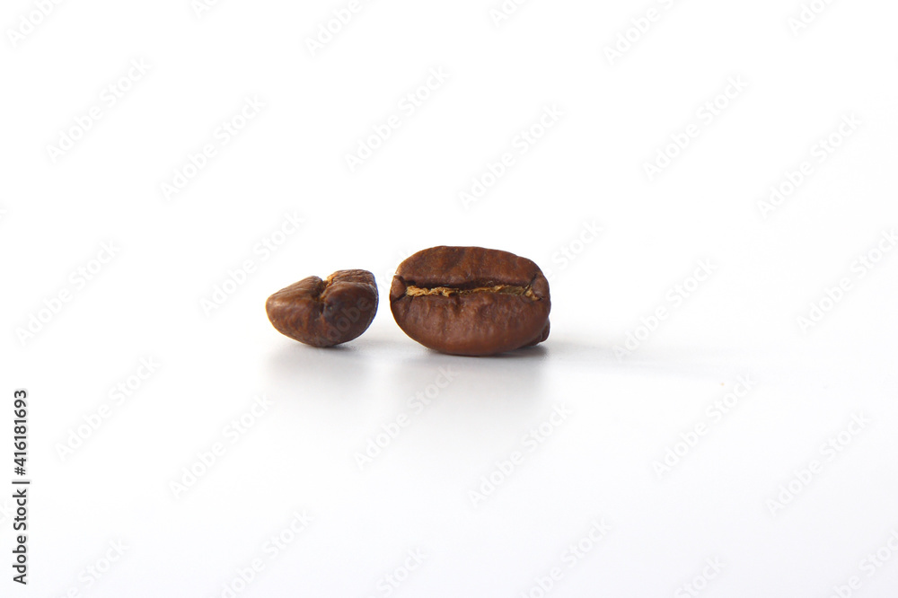 grain of aromatic black coffee on a white background. Background from two coffee beans, roasted coffee beans with selective focus close-up, place for text. grain of aromatic black coffee on a white background. Background from two coffee beans, roasted coffee beans with selective focus close-up, place for text.