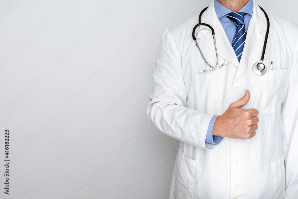 ELEGANT DOCTOR WITH THUMB UP FINGER, STETHOSCOPE, WHITE COAT, AND BLUE TIE. TRUSTED DOCTOR AND HEALTH INSURANCE CONCEPT. COPY SPACE. ELEGANT DOCTOR WITH THUMB UP FINGER, STETHOSCOPE, WHITE COAT, AND BLUE TIE. TRUSTED DOCTOR AND HEALTH INSURANCE CONCEPT. COPY SPACE.