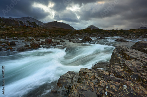 Long exposure of water with rocks in the foreground  winter vegetation on the River Sligachan on the Isle of Skye Scotland with the Cuillin mountain range in the distance  Isle of Skye  Scotland