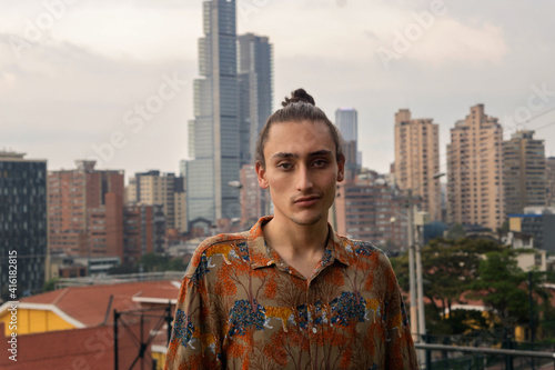 Portrait of young Hispanic man with the landscape of a city, Bogota urban cityscape with a young man looking at the camera, architectural landscape of a business city photo