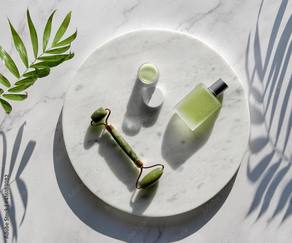Jade face roller and herbal infusion for facial massage therapy. Flat lay  on round marble podium on stone table with exotic palm leaf. Simple  arrangement, sunlight, long shadows Stock Photo | Adobe