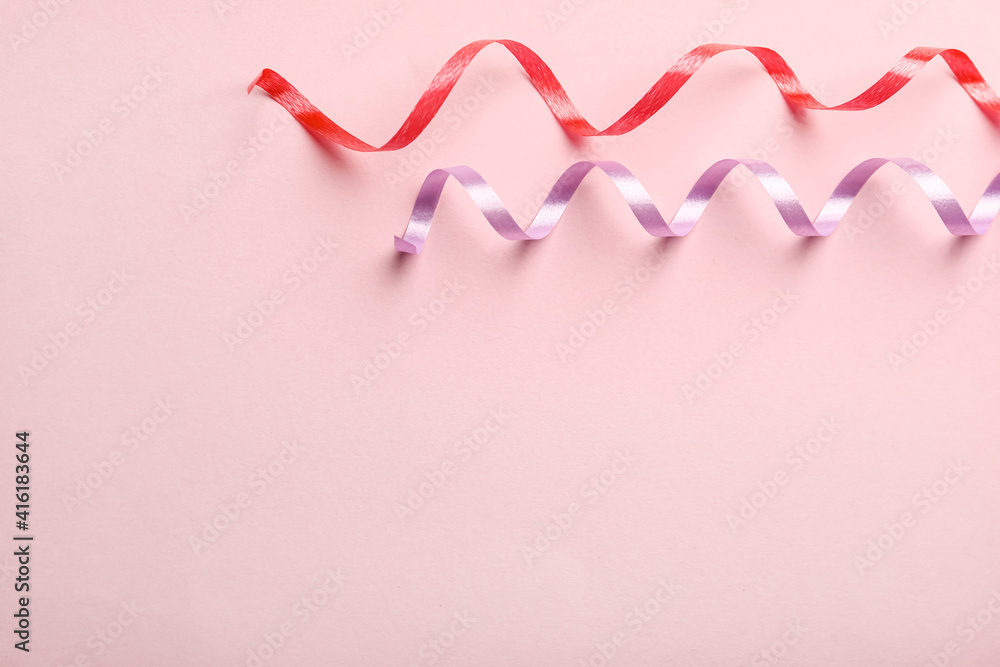 Colorful serpentine streamers on pink background, flat lay. Space for text